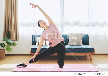 自宅のリビングでヨガポーズをする30代女性のフィットネスライフ 自宅のリビングでヨガポーズをする30代女性のフィットネスライフ 136939573