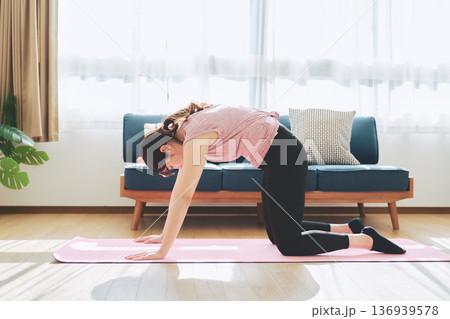 自宅のリビングでヨガポーズをする30代女性のフィットネスライフ 自宅のリビングでヨガポーズをする30代女性のフィットネスライフ 136939578