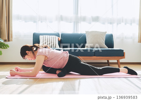 自宅のリビングでヨガポーズをする30代女性のフィットネスライフ 136939583