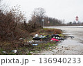 Illegal roadside dumping with tires plastic bottles and muddy abandoned landscape 136940233
