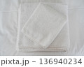 Folded white cotton towels on clean minimalist bed linen background 136940234
