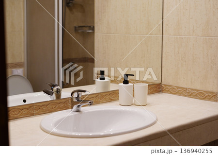 Modern bathroom sink with mirror soap dispensers and clean countertop Modern bathroom sink with mirror soap dispensers and clean countertop 136940255