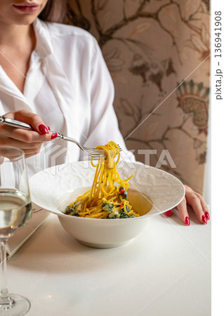 Woman eating pasta in elegant restaurant setting 136941908