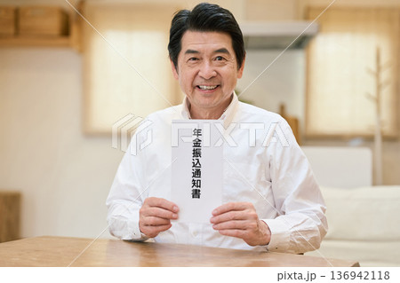 笑顔で年金振込通知書を持つアジア人シニア男性 136942118