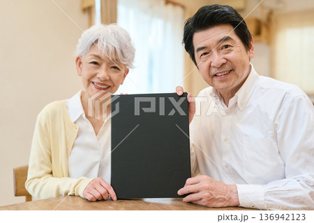 笑顔で黒いファイルを持つアジア人シニア夫婦 笑顔で黒いファイルを持つアジア人シニア夫婦 136942123