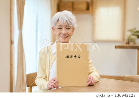 確定申告のファイルを持つアジア人シニア女性 確定申告のファイルを持つアジア人シニア女性 136942128