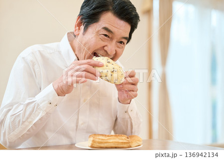 菓子パンを食べるアジア人シニア男性 136942134