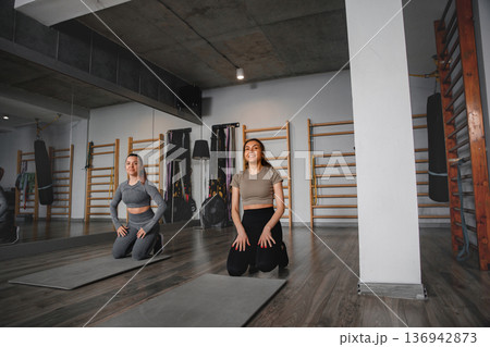 Women train together in gym while practicing yoga and exercising on mats 136942873