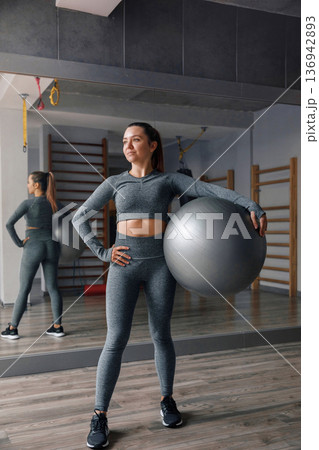 Woman stands with exercise ball in gym during training session for fitness and health 136942893