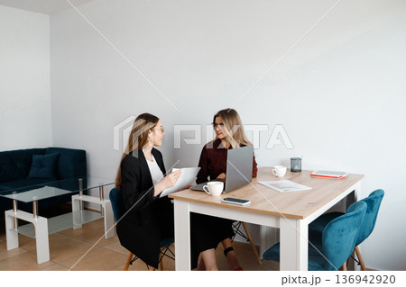 Women hold meeting in modern office while discussing project details during working hours 136942920