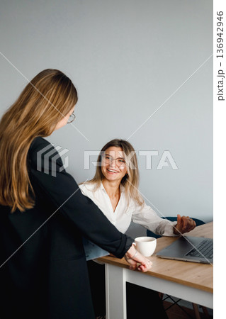 Portrait of two women engaged in discussion during a meeting in a business office setting 136942946
