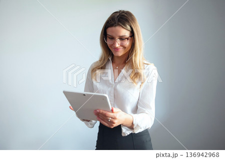 Woman using a tablet in a business office setting during working hours Woman using a tablet in a business office setting during working hours 136942968