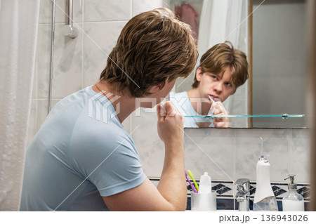Brushing teeth while looking at mirror reflection. Brushing Teeth 136943026