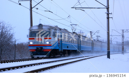 A suburban electric train drives at sunset through the countryside.  136945154