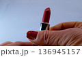 A woman's hand opens the red lipstick and unwinds it.  136945157