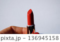 A woman's hand opens the red lipstick and unwinds it.  136945158