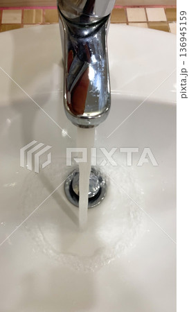 Water runs from the water tap in the bathroom. 136945159