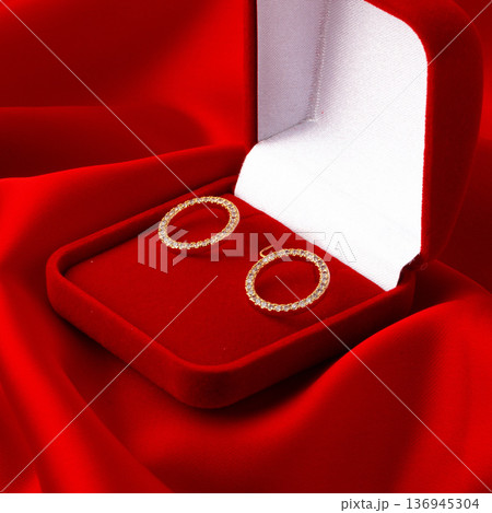 Elegant gold earrings in a red jewelry box on a red velvet cloth Elegant gold earrings in a red jewelry box on a red velvet cloth 136945304