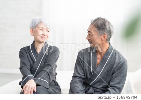 ガウンコート姿でベッドに座るシニア夫婦　ライフスタイルイメージ 136945704