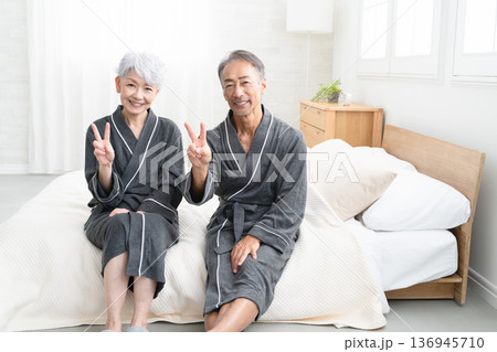 ガウンコート姿でベッドに座るシニア夫婦　ライフスタイルイメージ 136945710