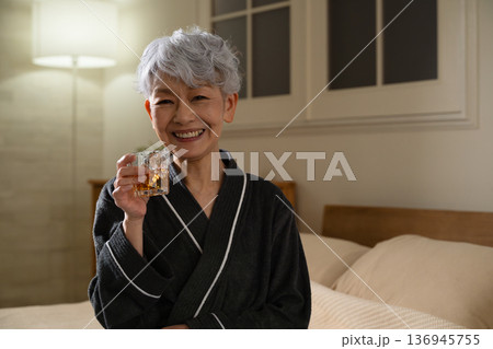 ガウンコート姿でロックグラスを持つシニア女性　ライフスタイルイメージ 136945755