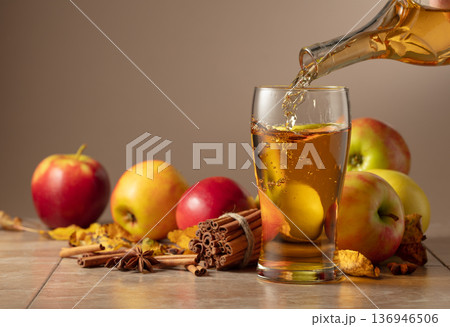 Apple cider is poured into a glass. Apple cider is poured into a glass. 136946506