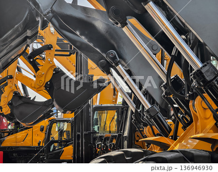 Construction equipment lined up at a dealership showing loaders and excavators ready for work in the afternoon sun Construction equipment lined up at a dealership showing loaders and excavators ready for work in the afternoon sun 136946930