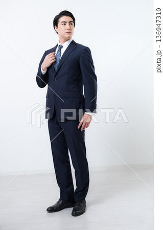 笑顔で襟元を整えるスーツの男性ビジネスマン全身 136947310