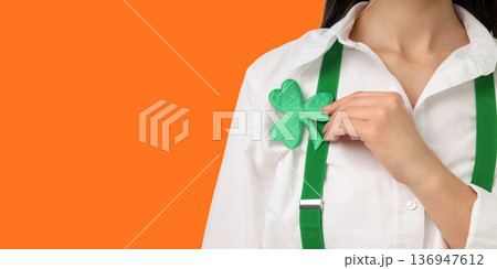 Woman wears white shirt and holds a shamrock for celebration 136947612