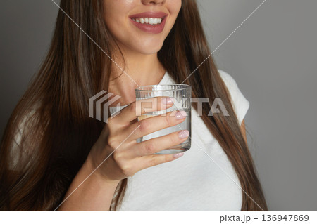 Close up smiling young woman holding glass of clean mineral water, happy beautiful female recommending drinking water 136947869