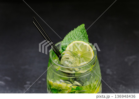 Fresh mojito cocktail with lime, mint and ice in glass on dark background 136948436