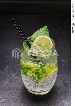 Fresh mojito cocktail with lime, mint and ice in glass on dark background Fresh mojito cocktail with lime, mint and ice in glass on dark background 136948444
