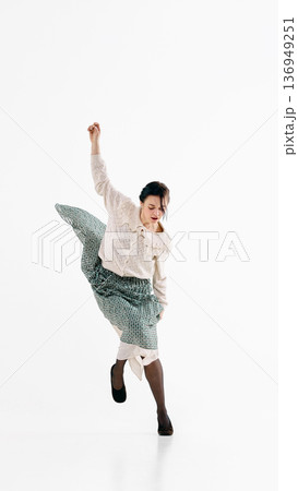 Woman in retro blouse and flowing green skirt jumping mid air on white studio background. Woman in retro blouse and flowing green skirt jumping mid air on white studio background. 136949251
