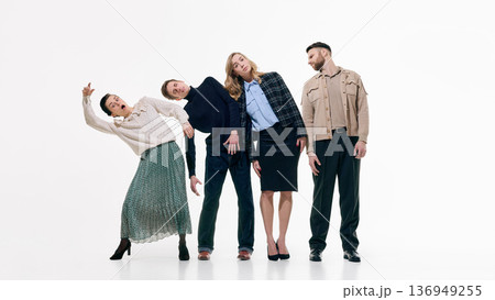 Four casually dressed people leaning sideways in synchronized pose on white background. Four casually dressed people leaning sideways in synchronized pose on white background. 136949255