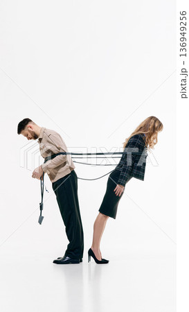 Businessman and businesswoman standing back to back tied together with rope on white studio background 136949256