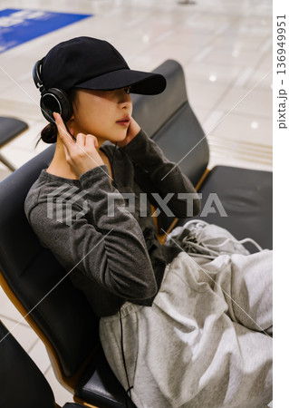 空港で音楽を聴く女性 ■撮影協力：関西国際空港（KIX） 136949951