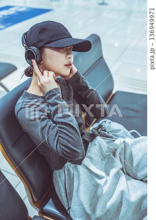 空港で音楽を聴く女性 ■撮影協力：関西国際空港（KIX） 136949971