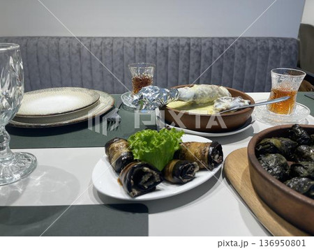 a table with plates of badrijani and glasses a table with plates of badrijani and glasses 136950801