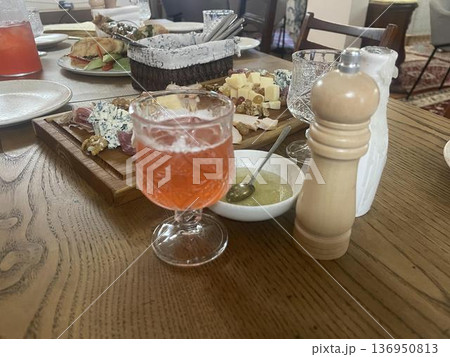 a table with a glass of wine and a plate of cheese 136950813