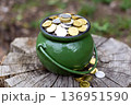 Green Pot Full of Golden and Silver Coins on a Rustic Wooden Stump 136951590