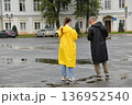 Two people in raincoats in a town square 136952540