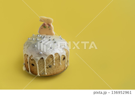 Festive Easter dessert with bunny topper and glossy icing on yellow background, cheerful seasonal styling with copy space 136952961