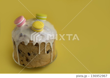 Bright Easter cake with icing drips and multicolored macarons on yellow background, joyful holiday dessert concept Bright Easter cake with icing drips and multicolored macarons on yellow background, joyful holiday dessert concept 136952967