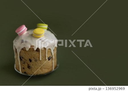 Holiday Easter dessert decorated with icing drops and colorful macarons against deep green backdrop, sophisticated spring concept 136952969