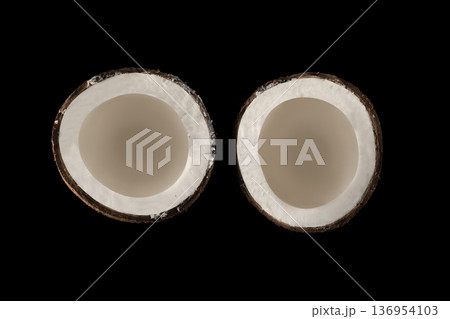 Coconut divided into two equal parts, view from the top, on a black background, isolated 136954103