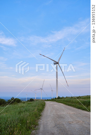 Wind Turbines on Hilltop Against Blue Sky 136955152
