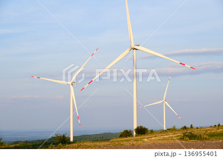 Wind Turbines on Hilltop Against Blue Sky 136955401