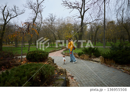 Woman talking on phone with dog in autumn park Woman talking on phone with dog in autumn park 136955508