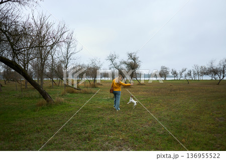 Woman playing with dog in autumn field Woman playing with dog in autumn field 136955522