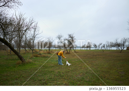 Woman playing with dog in autumn field Woman playing with dog in autumn field 136955523